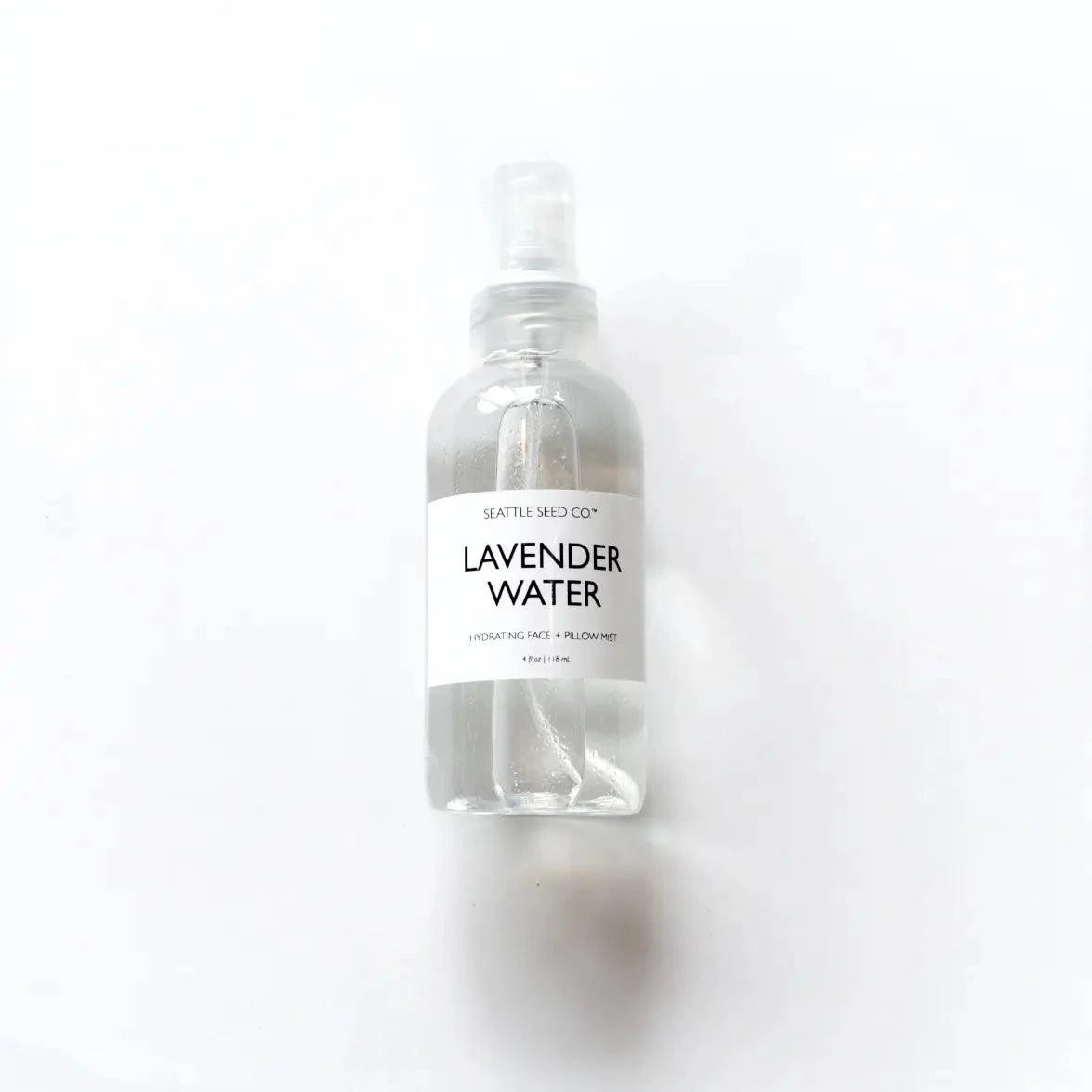 Lavender Face + Pillow Mist in a clear plastic spray bottle with a white label and black lettering, containing lavender water.