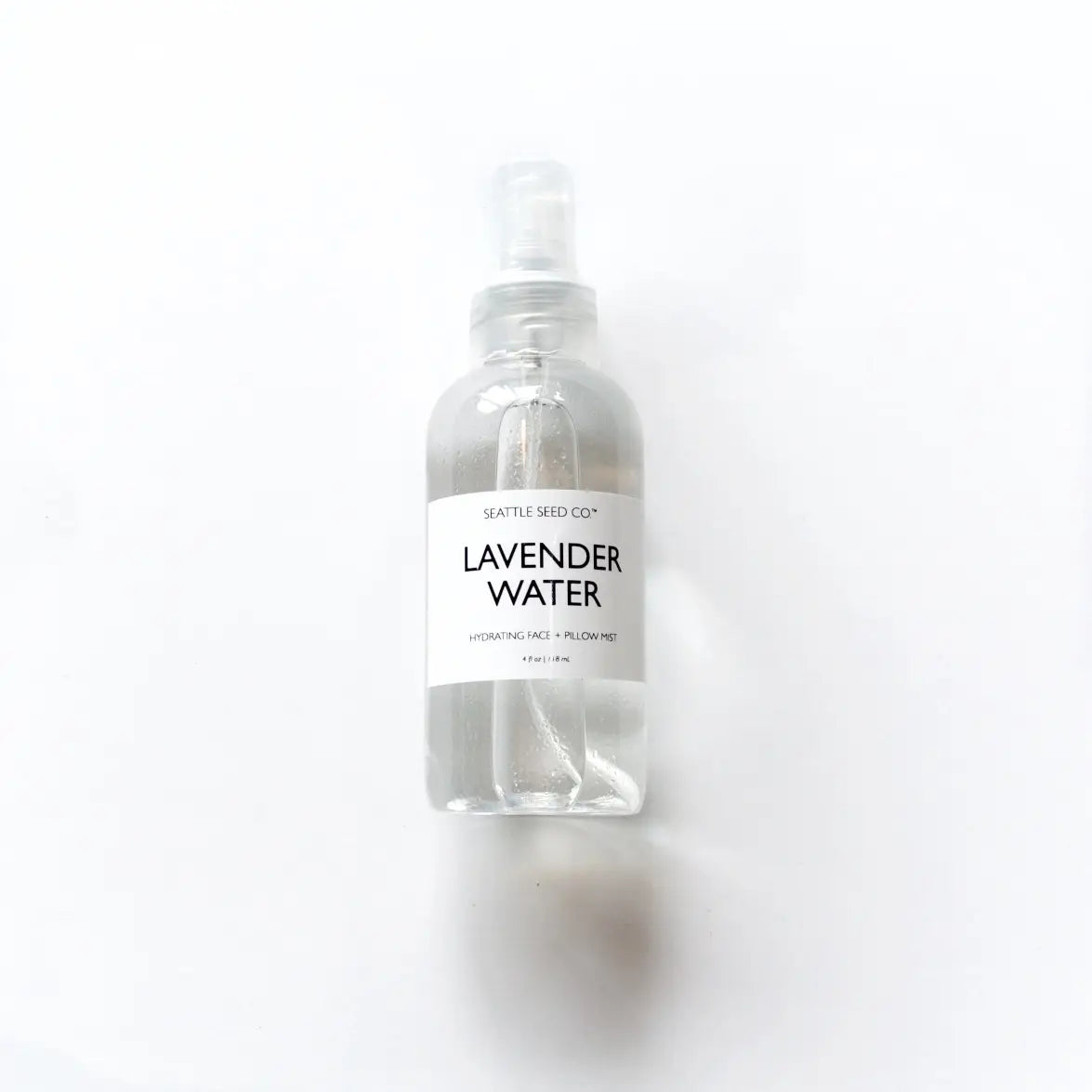 Lavender Face + Pillow Mist in a clear plastic spray bottle with a white label and black lettering, containing lavender water.